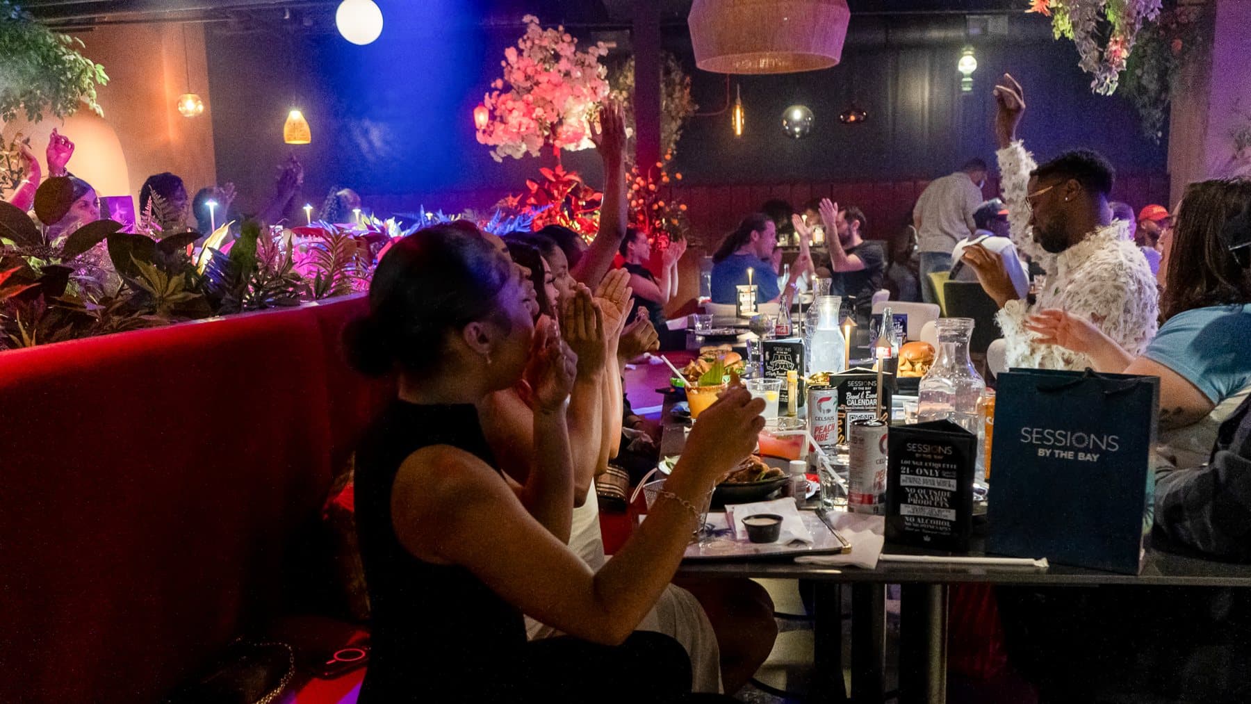 Guests clapping along at a long table during a show in the lounge