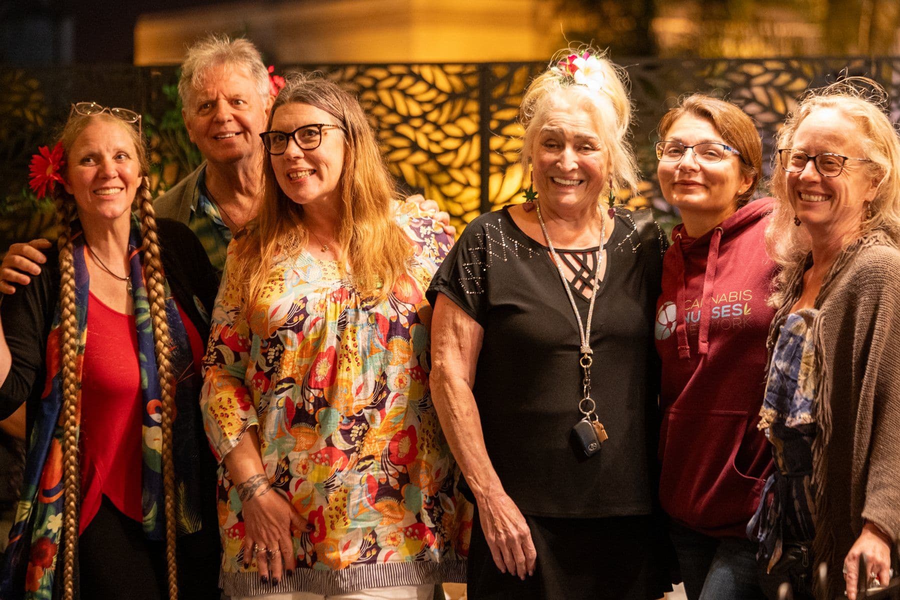 Six friends smiling together for a group photo at night