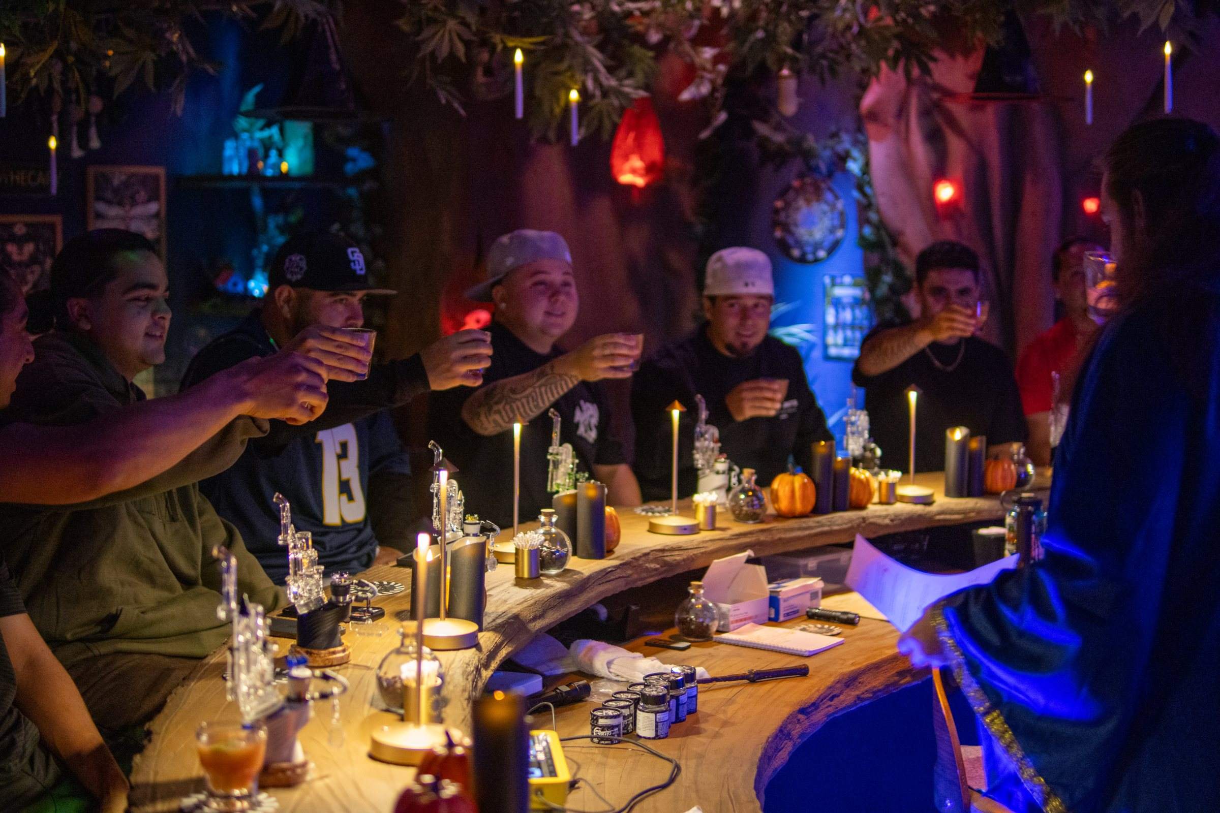 Guests smiling along the long wooden bar in Everburn Woods, dab rigs and candles in front of them